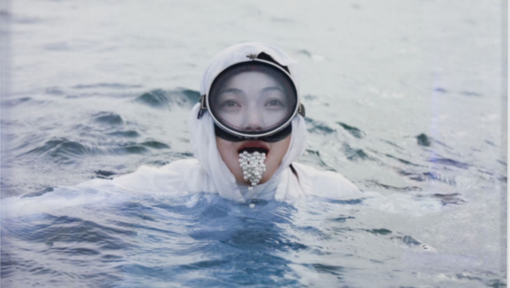 Woman swimming in sea with pearls falling out of mouth 