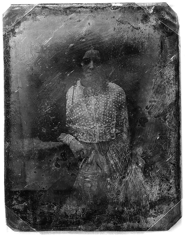 Daguerreotype portrait of a young girl in a dress, standing with her arm resting on a table