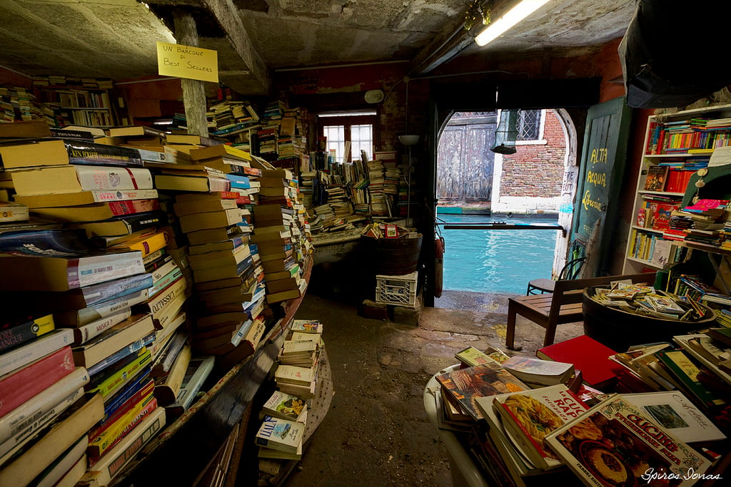 piles of books in a books store looking over the canal