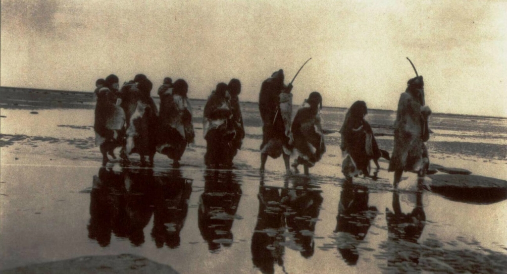 Group of Amazonians walking along water's edge.