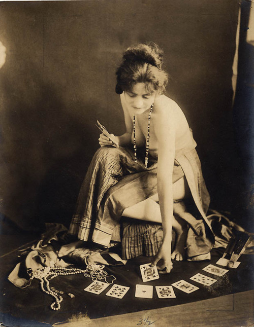 1920s woman in silk dress lays tarot cards on floor