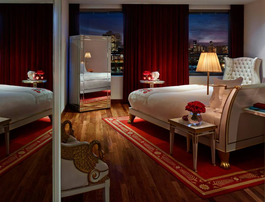hotel bedroom with large windows overlooking city