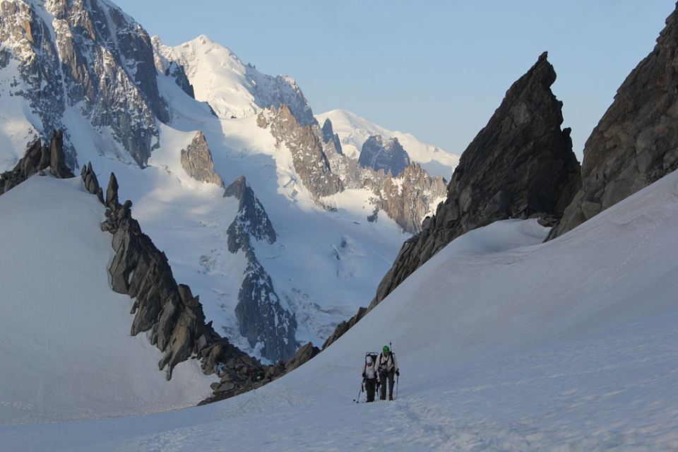 Individuals hiking on a snowy trail in the mountains