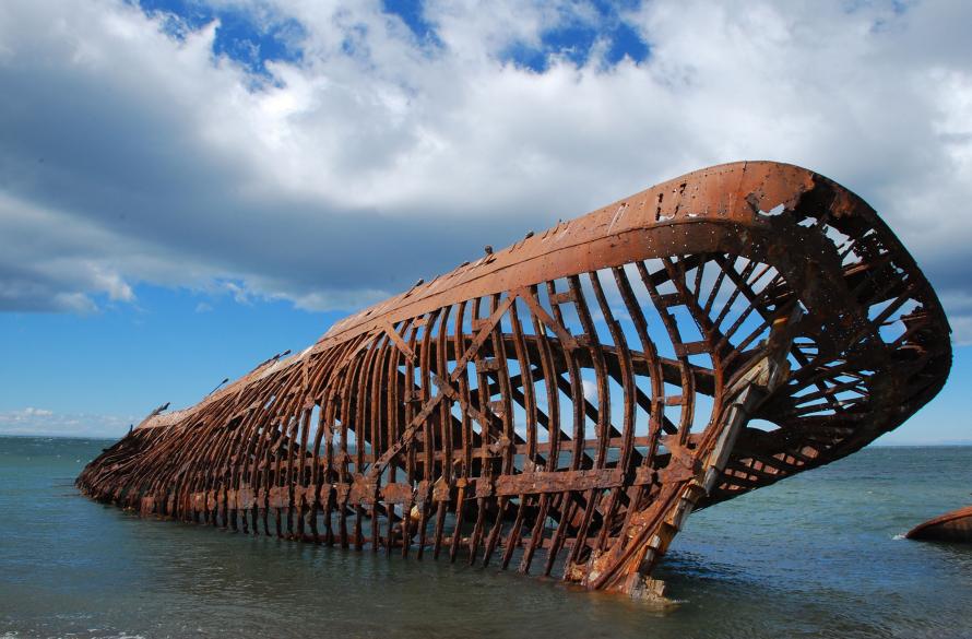 Frame of rusted ship hull partially in water.
