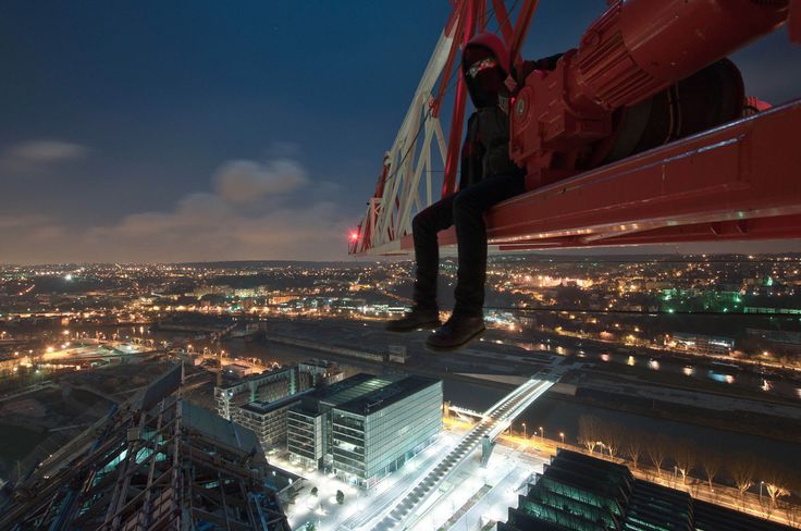 Man sitting on crane above city 