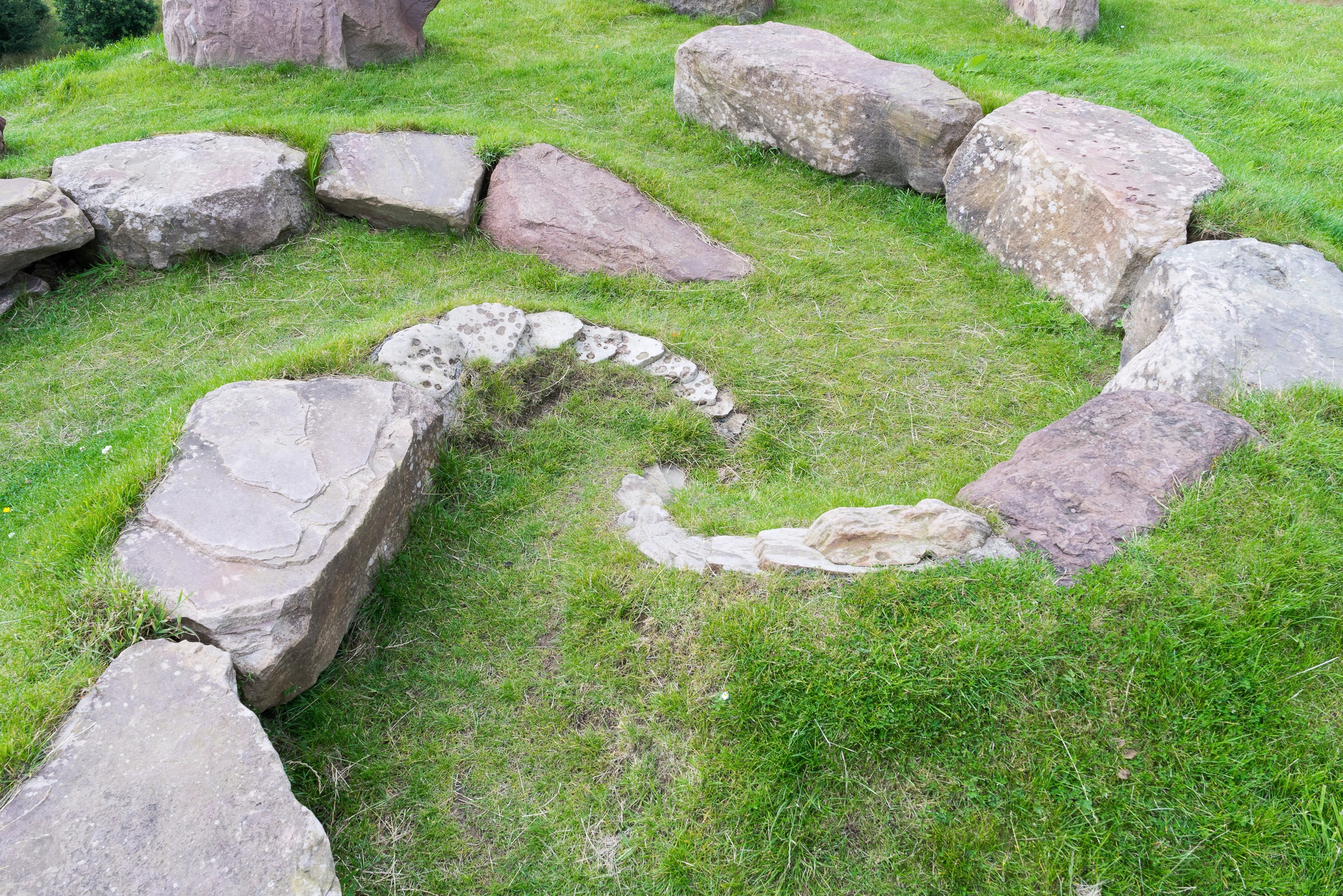Stones arranged in a spiral on green grass.