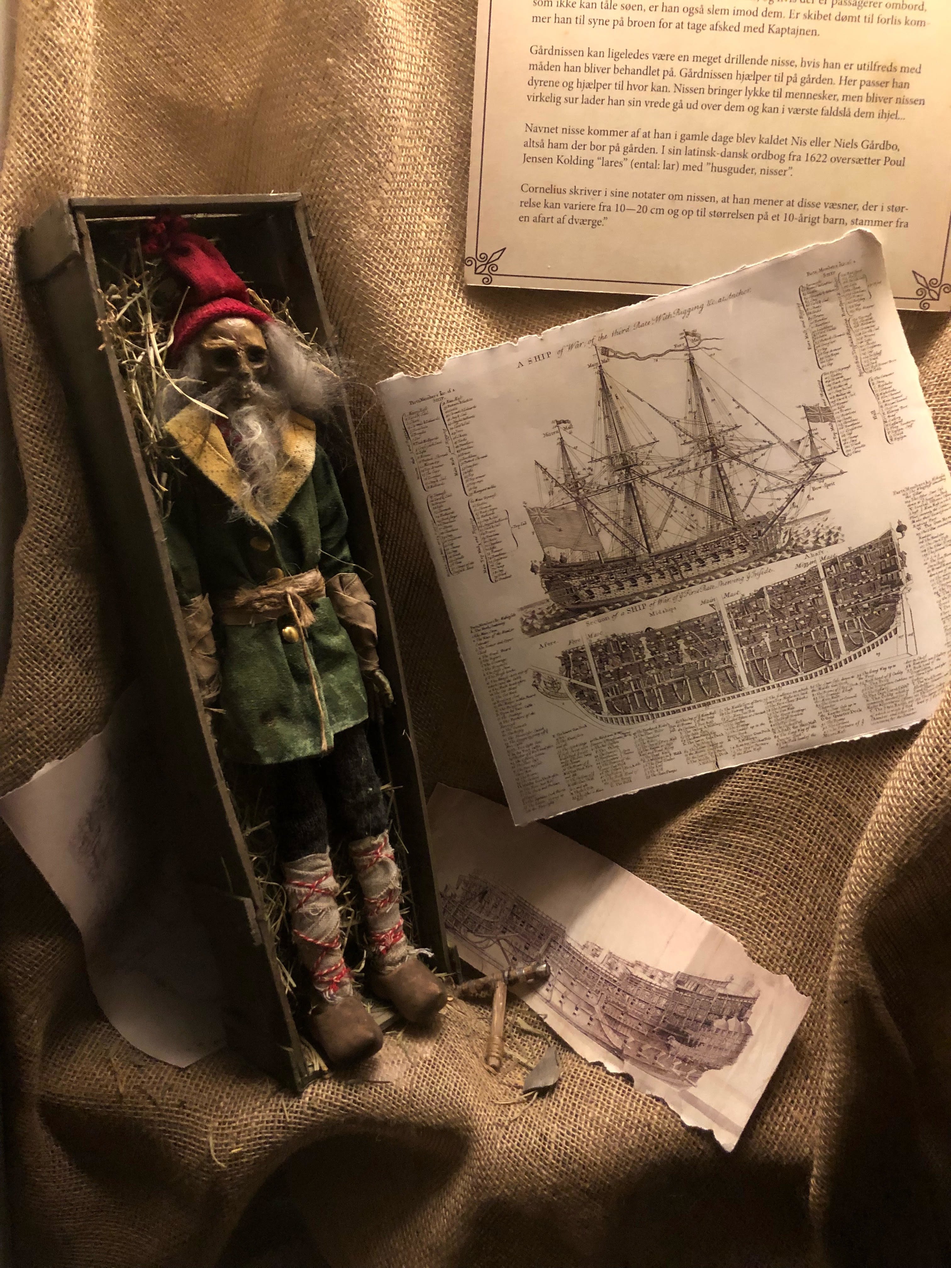 A bearded doll in a box with illustrations of ships.