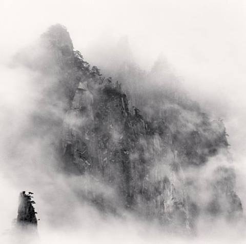 Black and white mountain shrouded in fog.