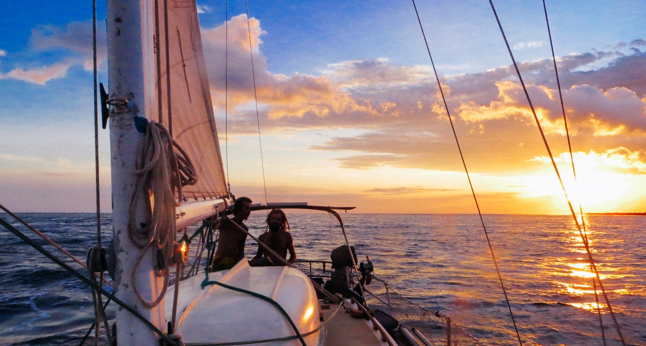 A sailboat on the ocean with a sunset in the background