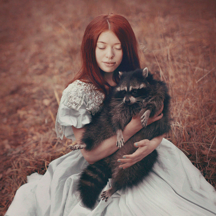 Woman in dress holding a raccoon.