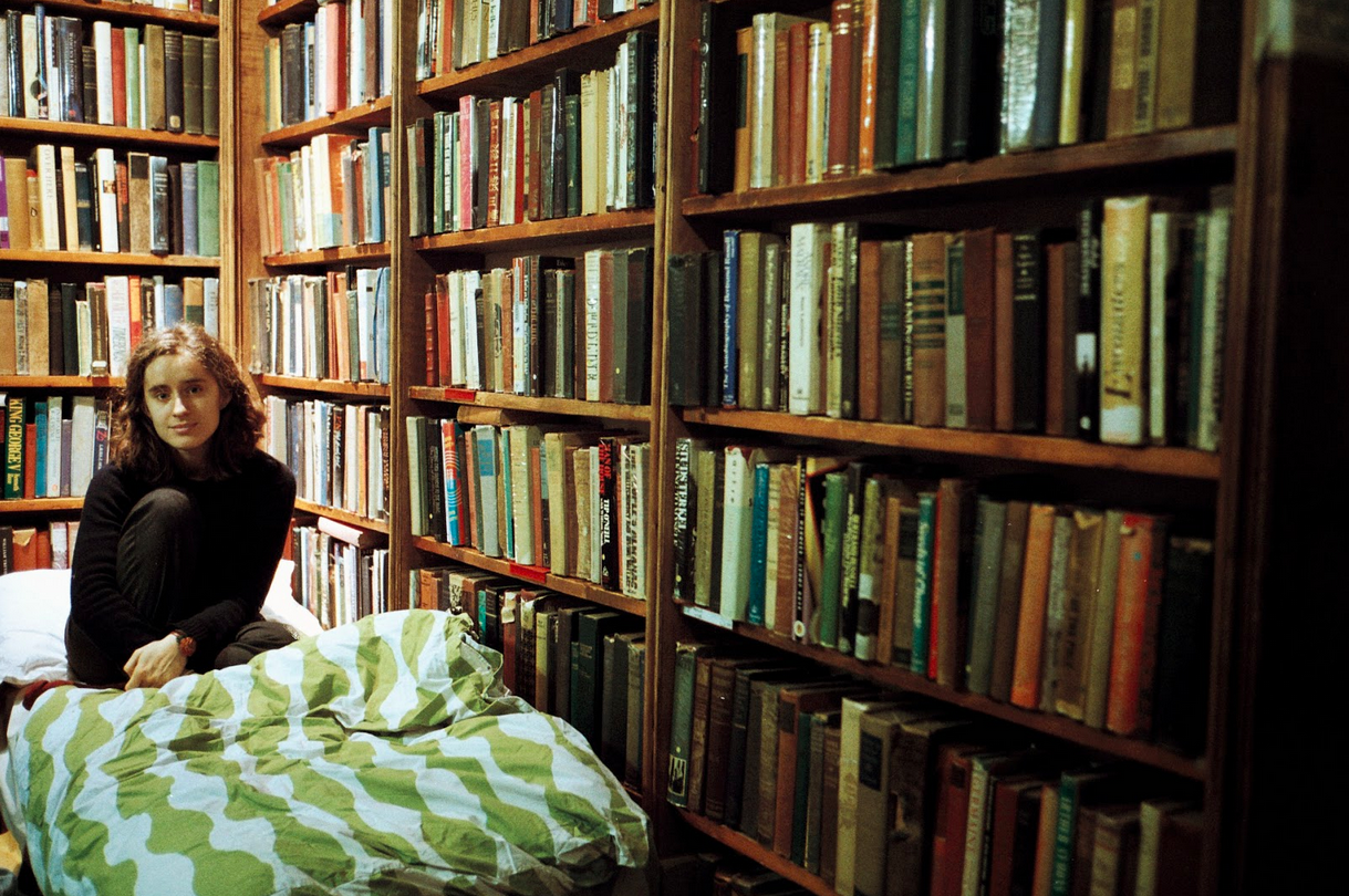 A woman sitting on a bed in a library