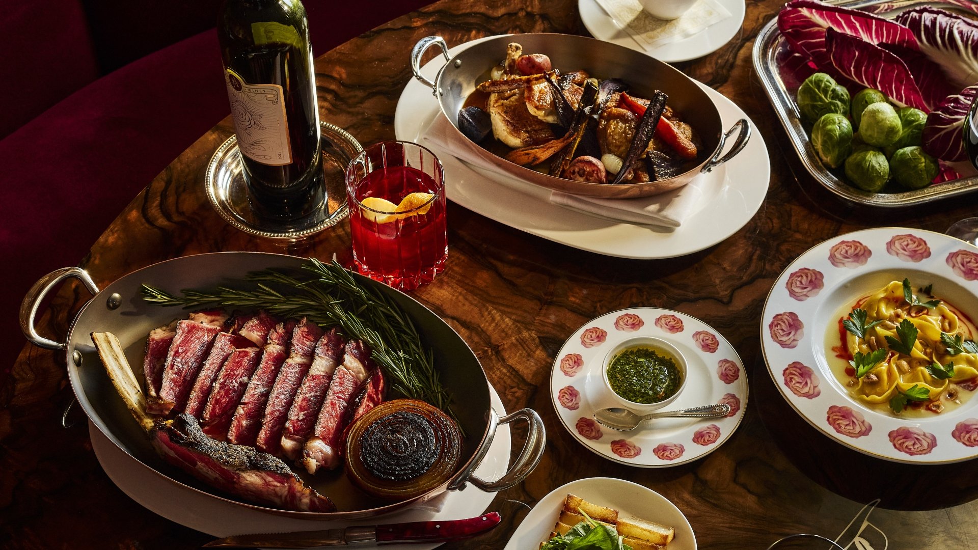 Thanksgiving dishes plated on rose plates with meat and wine