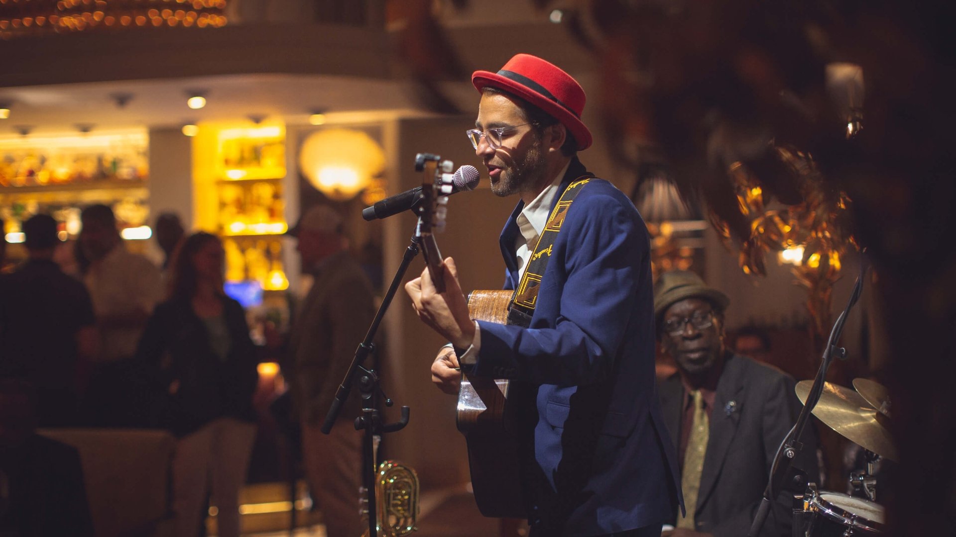 man in a red hat singing on a small stage