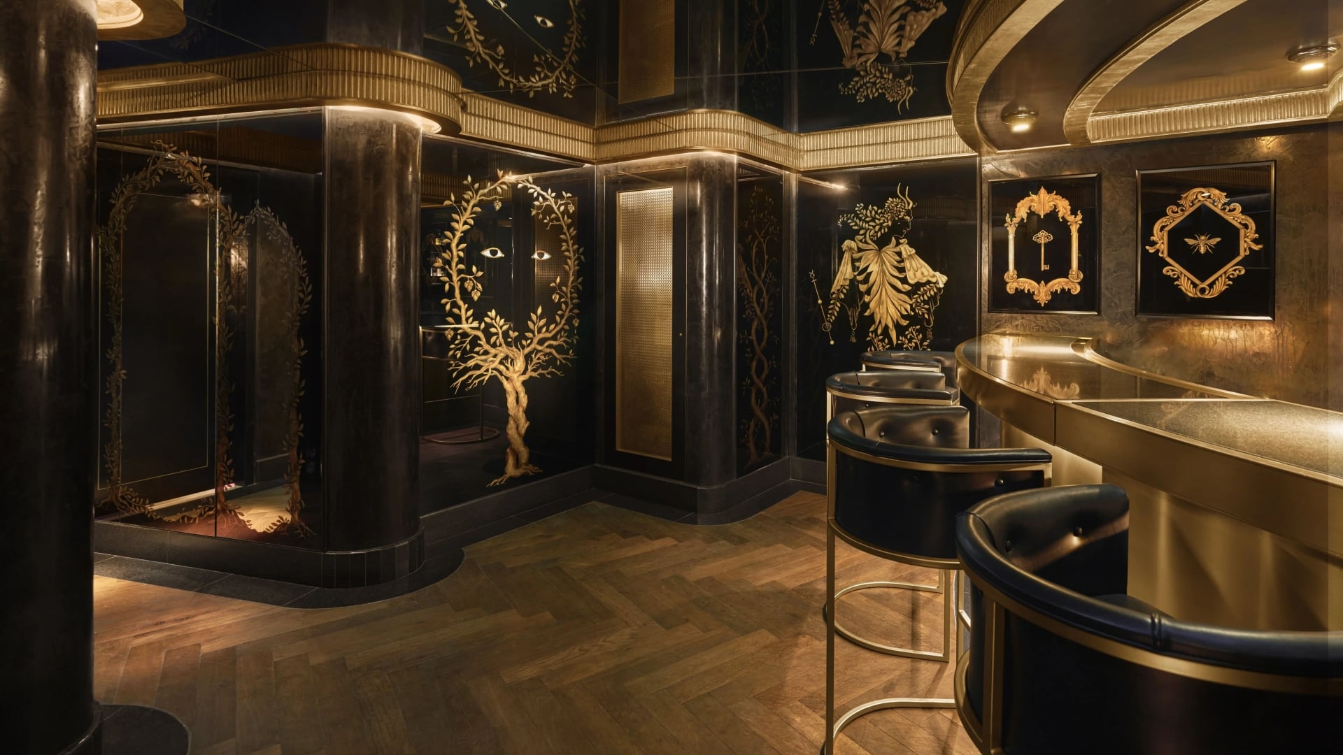 A luxurious bar with dark walls, gold accents, and stools.