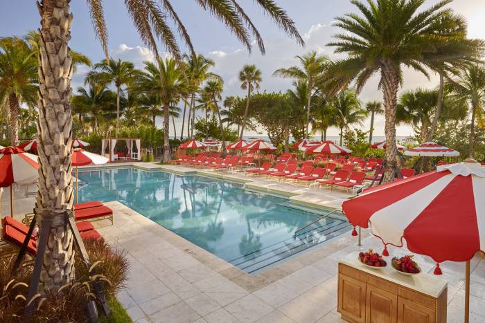 hotel pool surrounded by palm trees and umbrellas