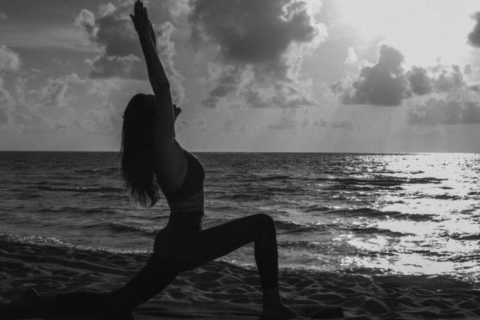 Woman doing yoga on the beach with a view of the ocean