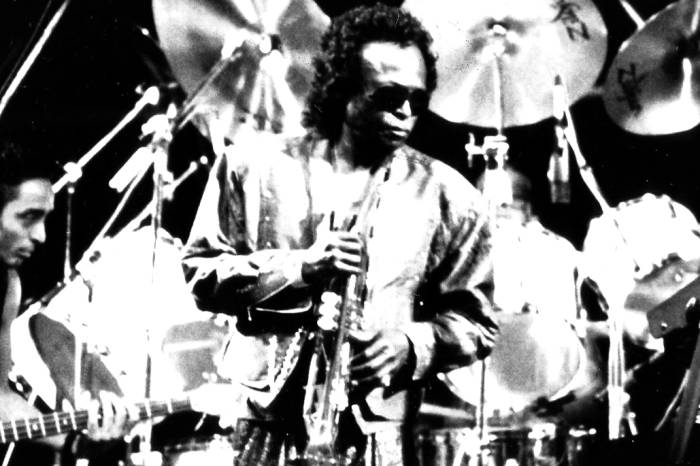 Jazz singer, Miles Davis, performing in front of a band