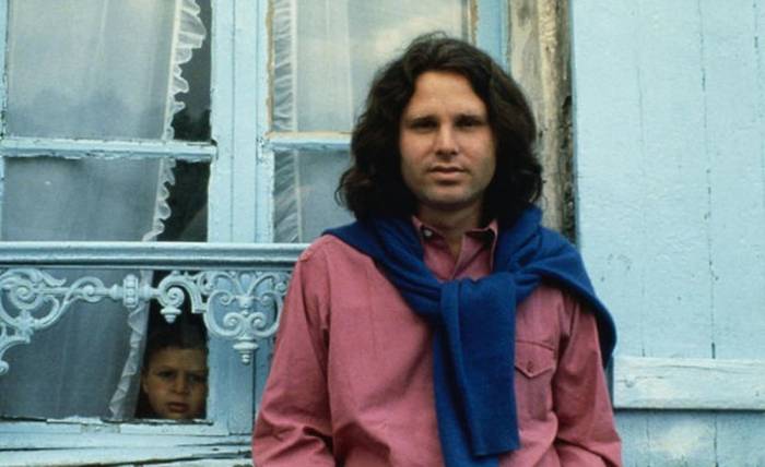 The Doors singer Jim Morrison in pink shirt and blue sweater tied over shoulders