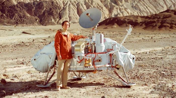 A man standing beside a vintage space rover