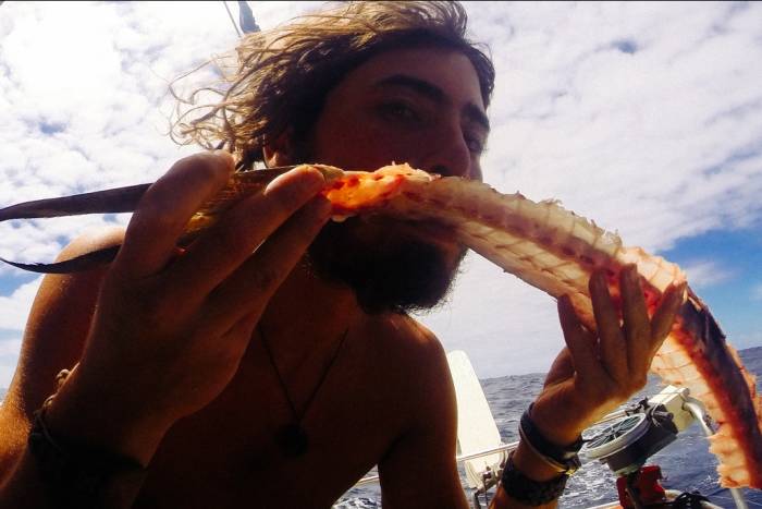 A man eating a large crab leg on the ocean