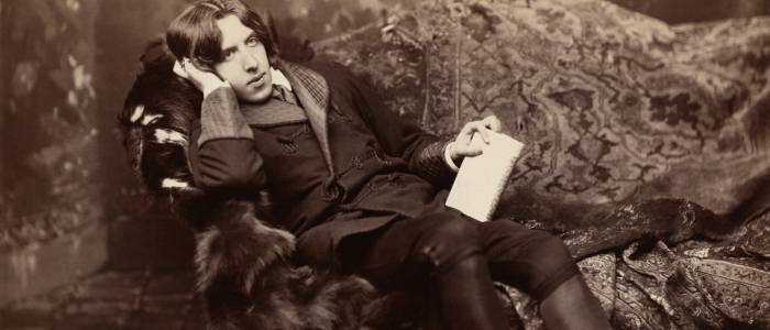 A man sitting in a fur covered chair with one hand on his head and book in the other hand