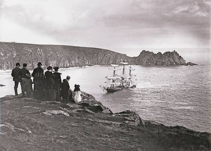 People on hill looking at shipwreck