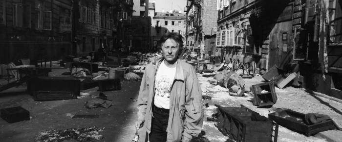 Director Roman Polanski on film set of raided European street.