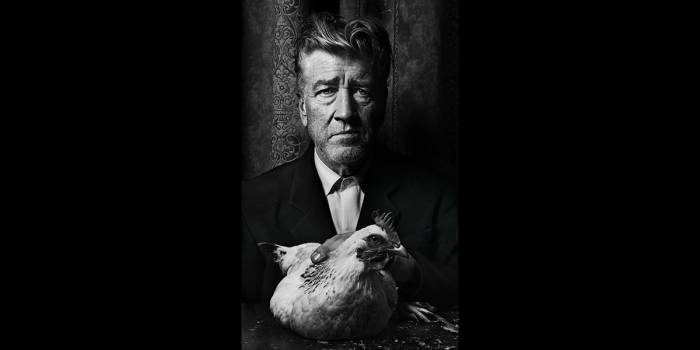 Black and white image centered on a photo of a man holding a chicken. 