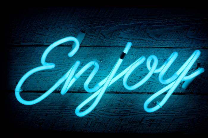 Blue neon sign shaped into the word "enjoy".