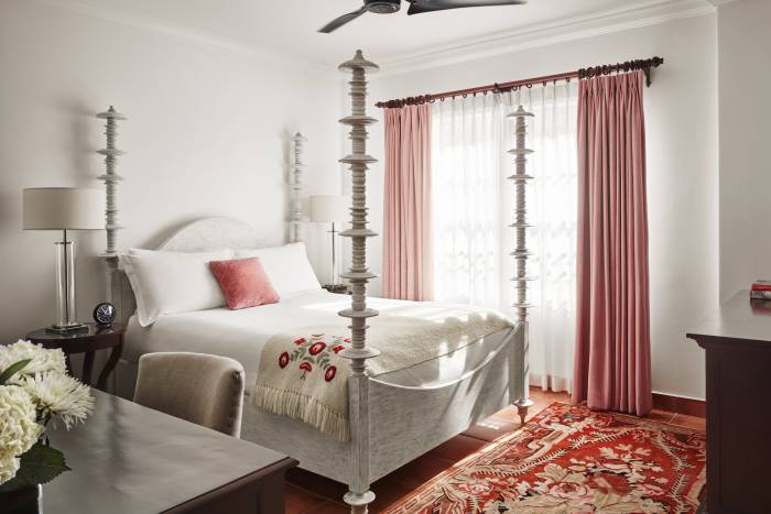 queen bed with four posts and pink curtained windows and red and gold carpet