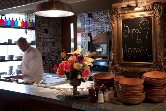 server scoops ladle of food into dish behind bar with flowers and chalkboard sign