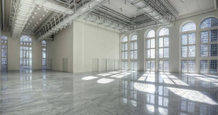 expansive white room with industrial ceiling and floor to ceiling windows