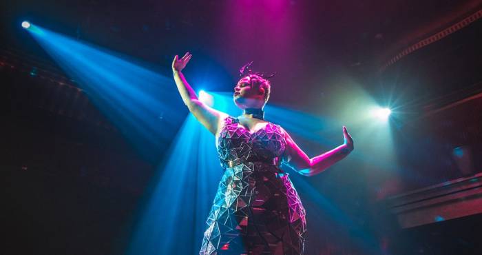 samsara performer in geometric dress holds arms out to their sides