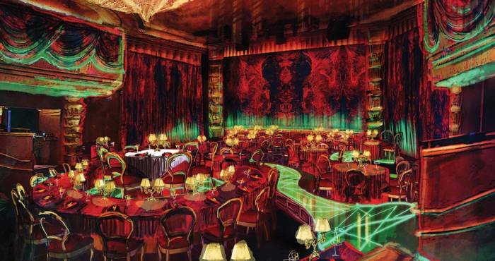 red and yellow light bathes an indoor theater seating area with green lit walking paths through the seats