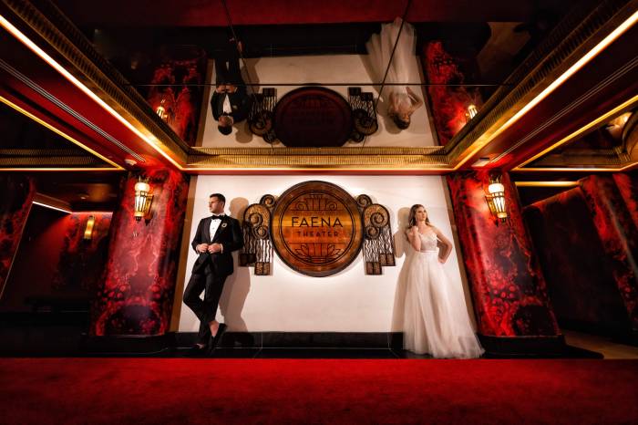 bride and groom stand on either side of Faena Theater sign
