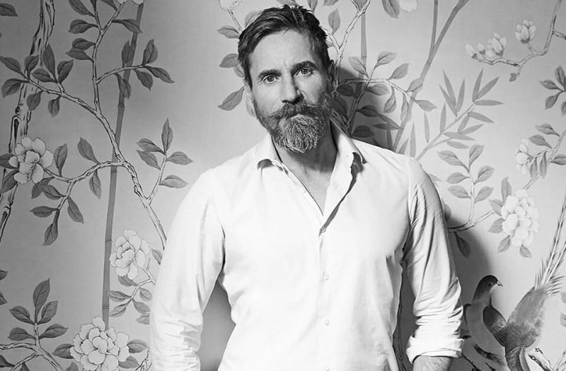 Peter Mikic standing in front of a wallpapered wall