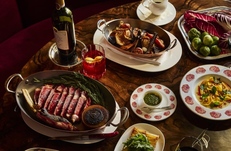 Thanksgiving dishes plated on rose plates with meat and wine