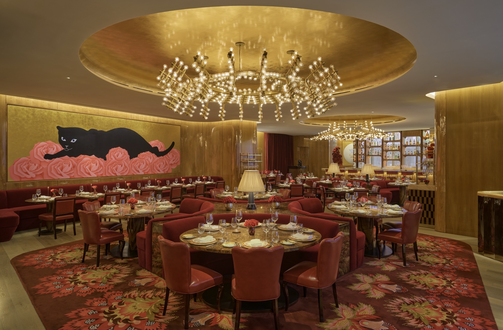 The dining room at La Boca, with gold walls and a mural featuring a black cat
