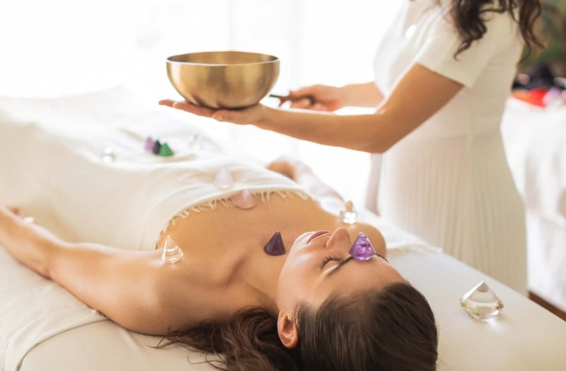 woman lays on table receiving crystal treatment by spa worker