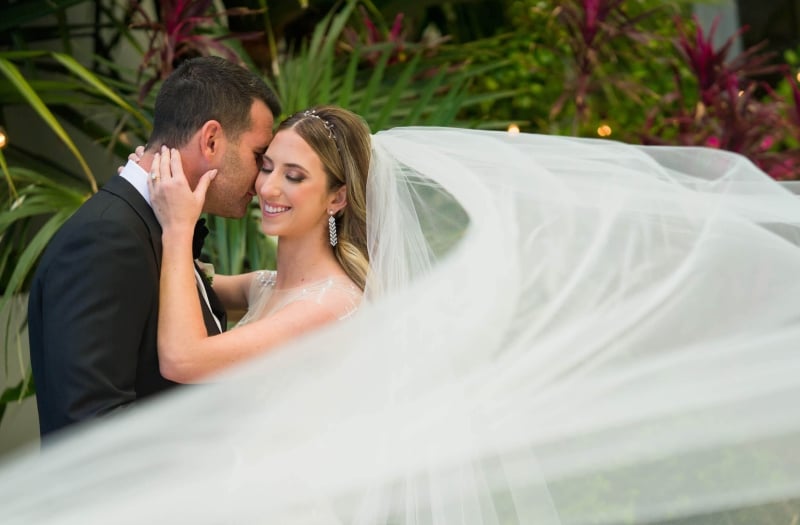 Husband and wife embracing with her veil flowing in front of them