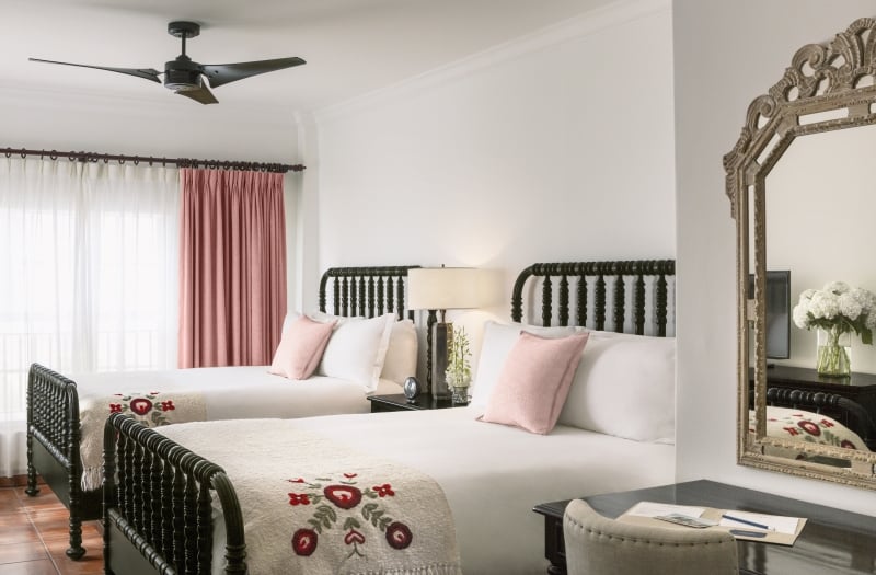 two beds with white sheets with mirror in foreground