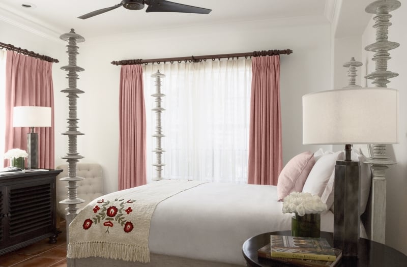 queen bed with four posts and pink curtained windows