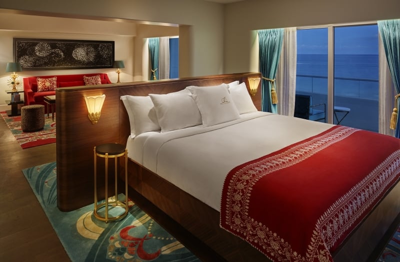bed in hotel suite at night with windows to the ocean