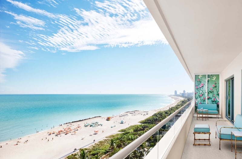 turquoise furniture sits on balcony with beach in the background