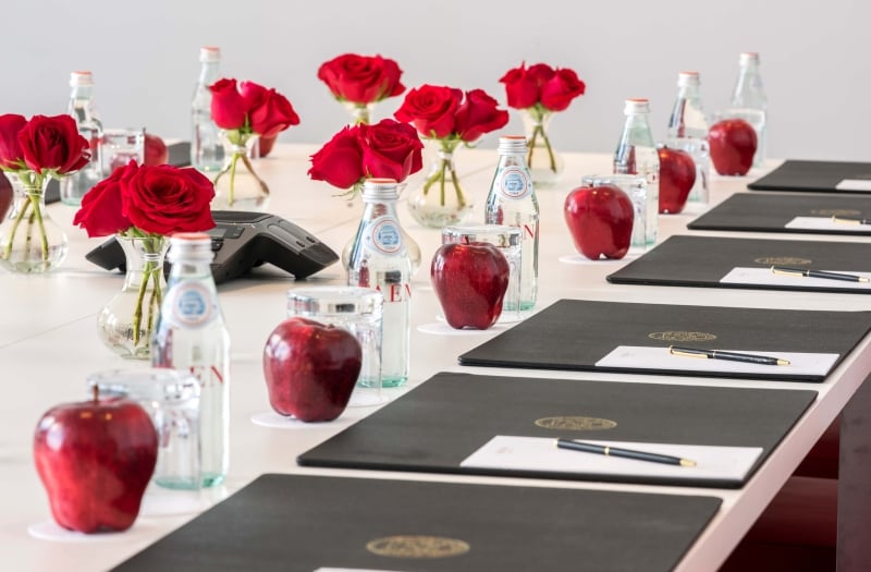 long table set up with padfolios, flowers and snacks