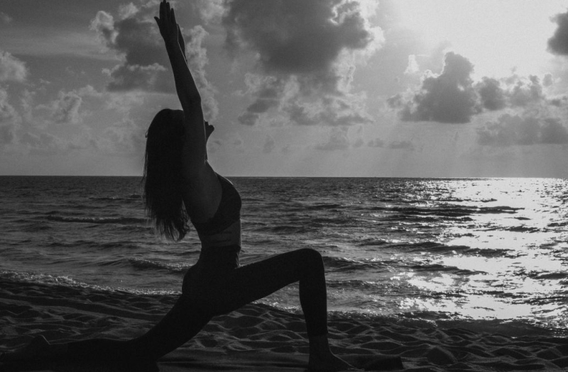 Woman doing yoga on the beach with a view of the ocean