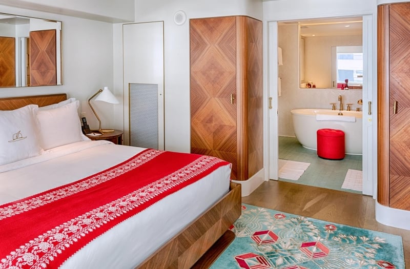 bed with view of bathtub in bathroom in the background