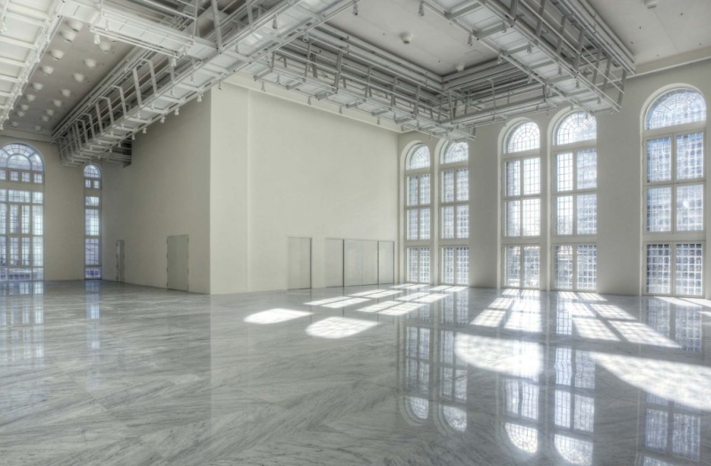 expansive white room with industrial ceiling and floor to ceiling windows
