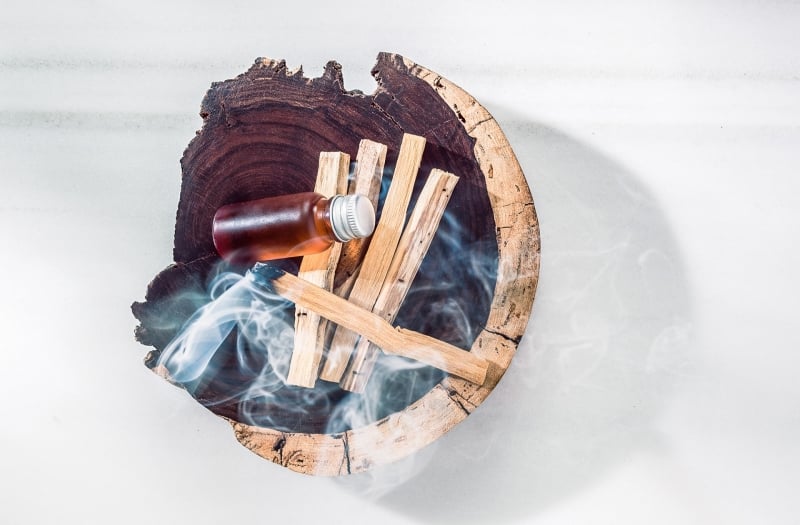 wooden bowl with wood smoking and small bottle