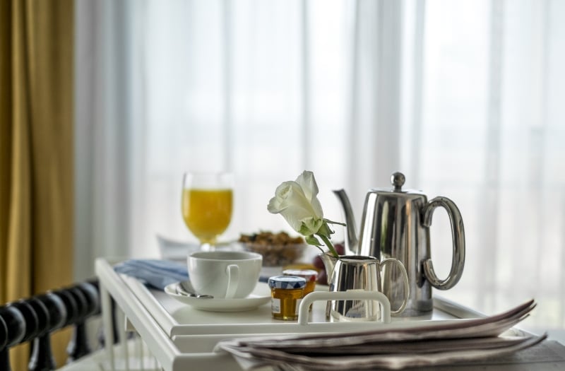 breakfast on a tray in front of curtained window